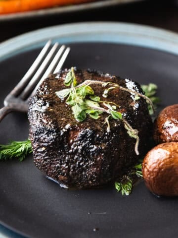 coffee rubbed filet mignon on black plate with fork