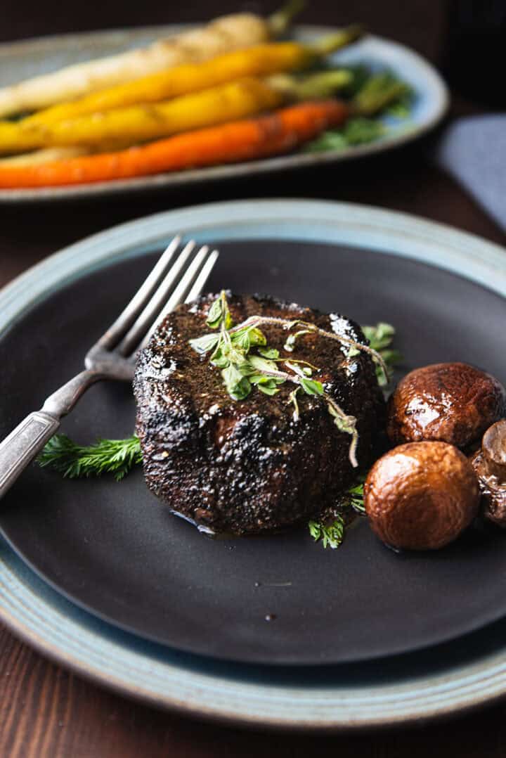 coffee rubbed filet mignon on black plate with fork