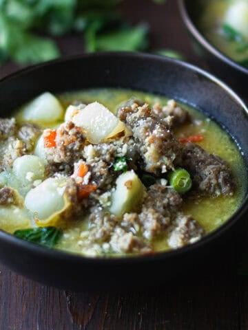Italian sausage soup served in a bowl with potatoes and vegetables