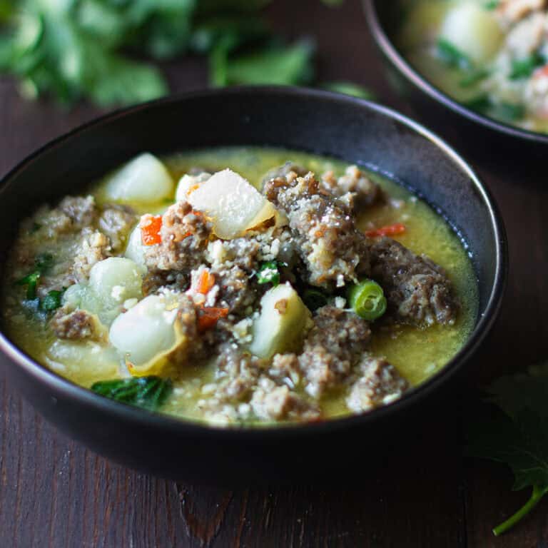 Italian sausage soup served in a bowl with potatoes and vegetables