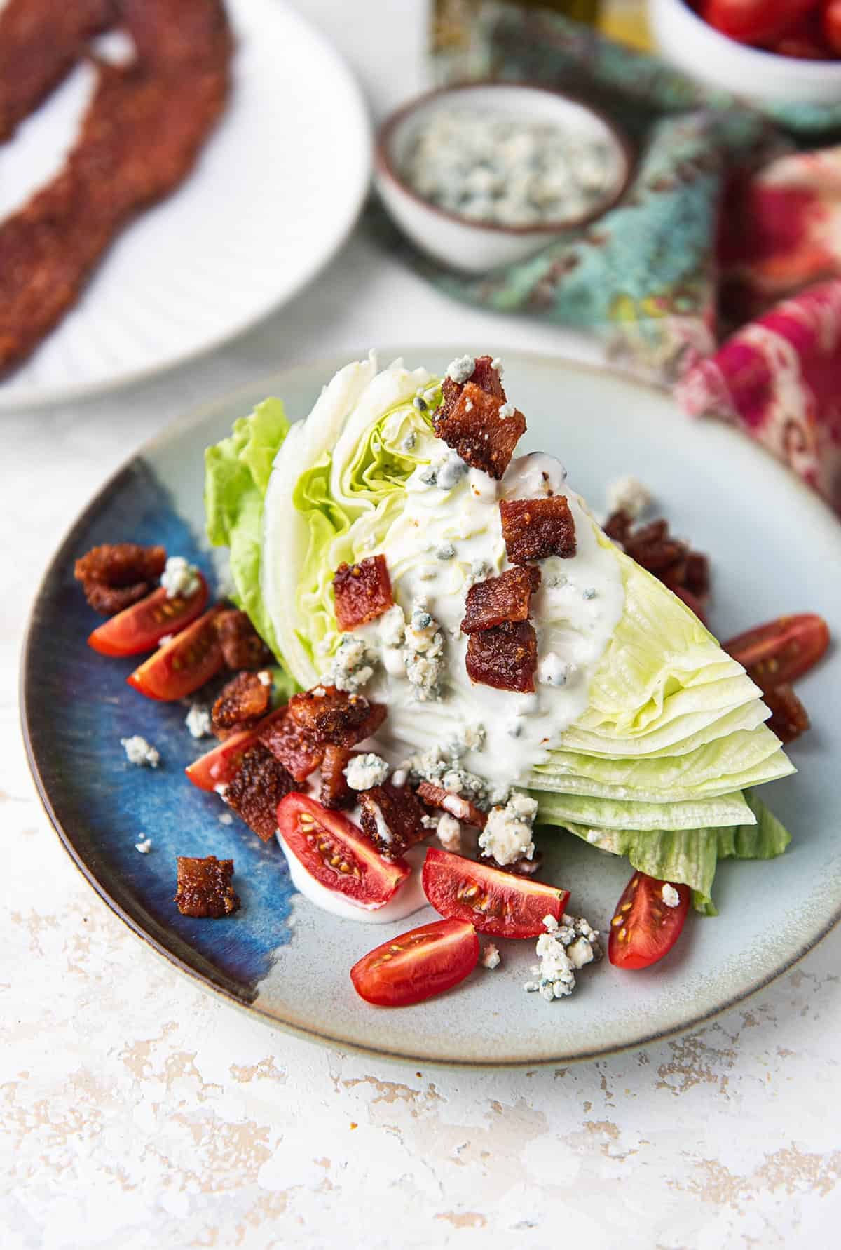 overhead view of a wedge salad with blue cheese dressing, candied bacon, and cherry tomatoes